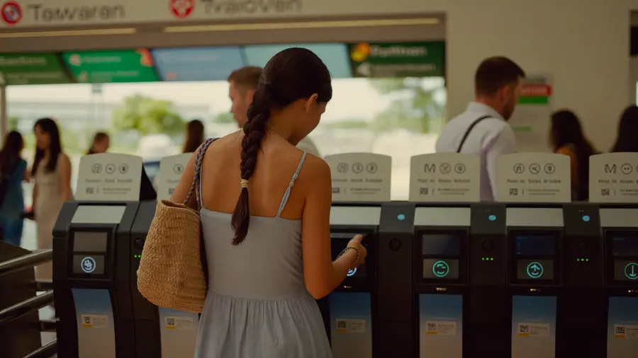 Cestující se zastavila před řadou turniketů v metru a čte značení nad čtečkami karet